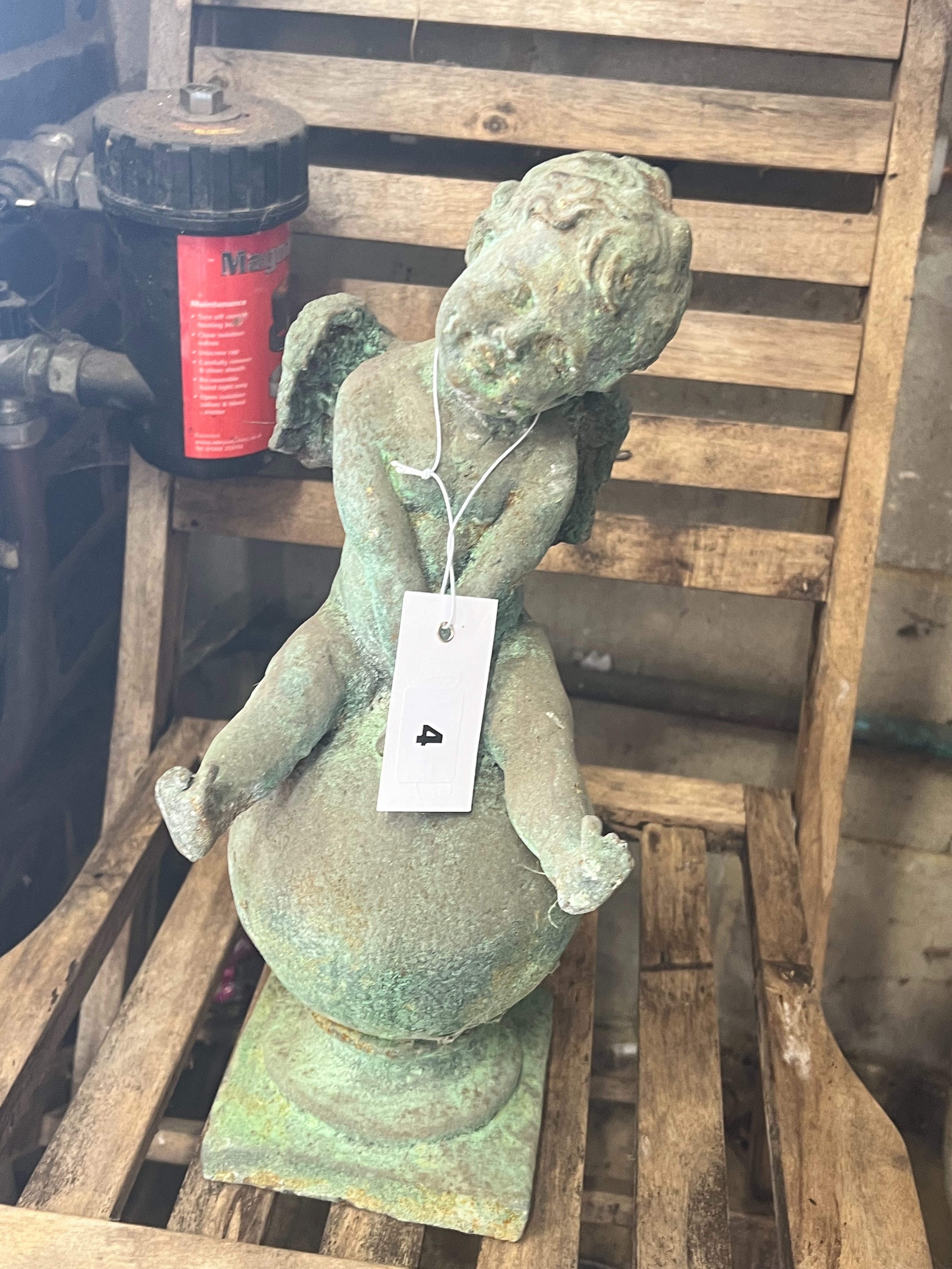 A cast iron cherub and orb garden ornament, height 38cm